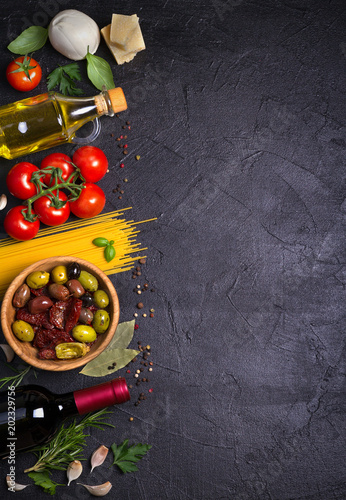 Selection of healthy food. Italian food background with spaghetti, wine, mozzarella parmesan cheese, olives, tomatoes and rosemary. Vegetarian food banner. overhead, vertical