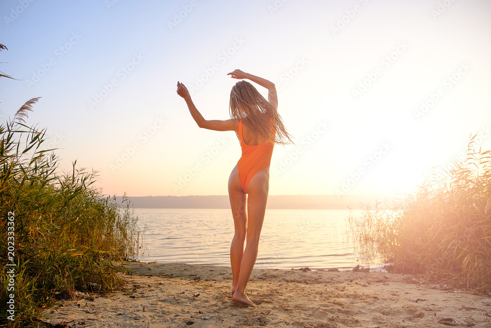 Φωτογραφία Attractive girl in swimsuit on the beach at sunrise