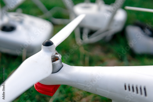 view of a flying white professional quadcopter drone camera with green grass in background, aerial photographer equipment, aircraft, rc, remote controller, transmitter photo