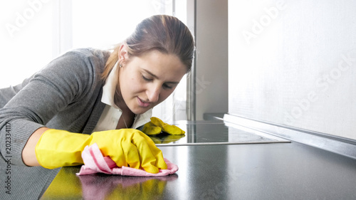 Portrait of young housewife scrubbing kitchen countertop with force