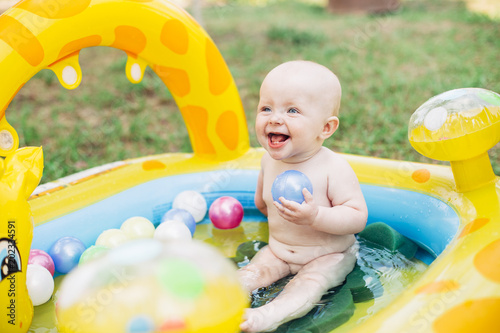 Little baby girl playing in the swimming pool. Summer. Smiling.