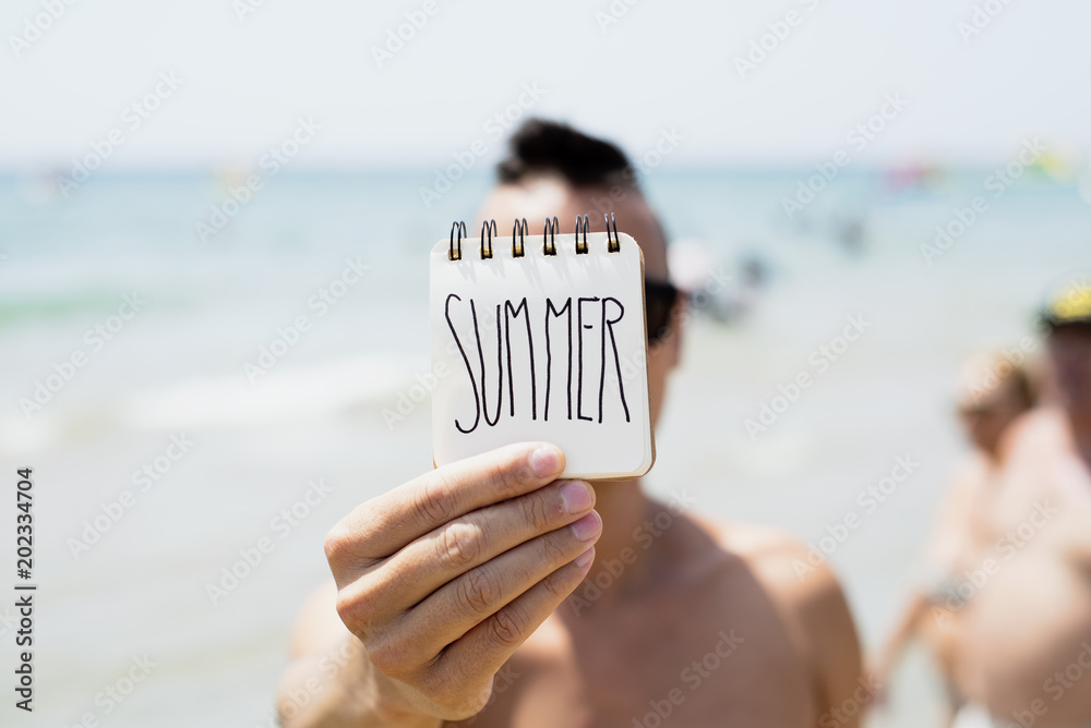 Fotografie young man with a note with the word summer.