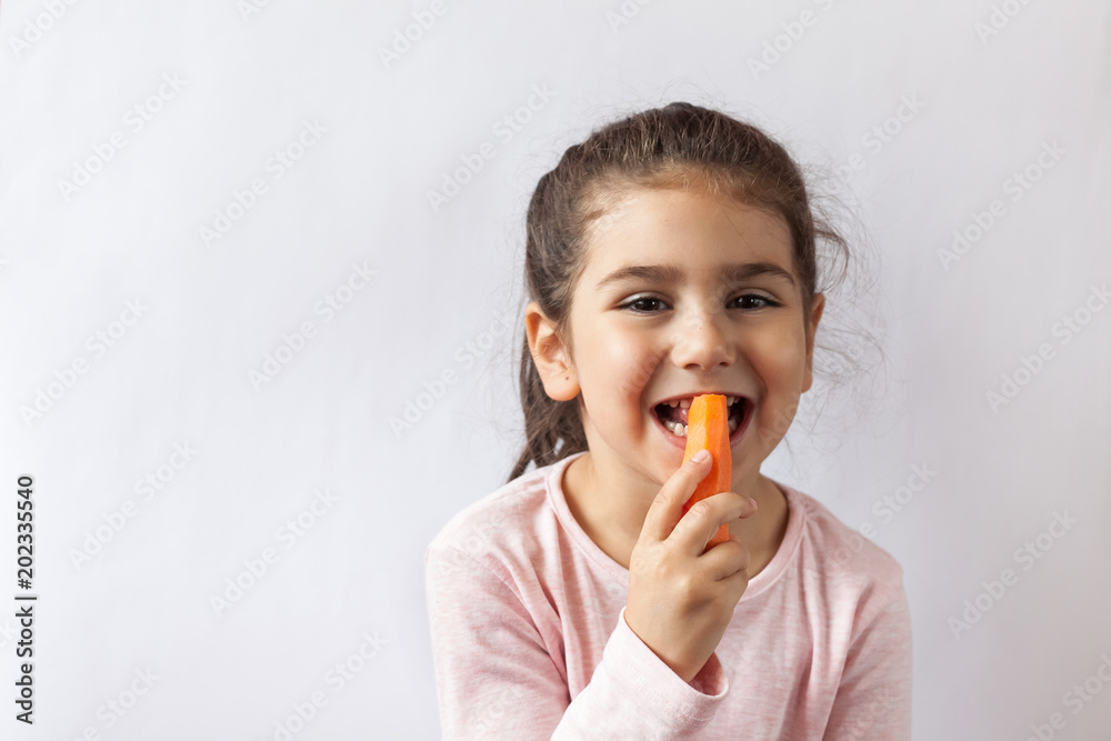 Happy little child girl eating fresh vegetables. Isolated portrait on white background. Healthy teeth. Happy little child girl eating fresh vegetables. Isolated portrait on white background. Healthy teeth.