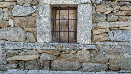Ventana con barrotes en una fachada de casa de piedra