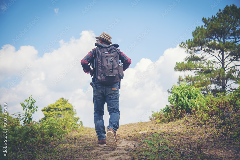 Young Man Traveler with backpack relaxing outdoor with rocky mountains on background Summer vacations and Lifestyle hiking concept