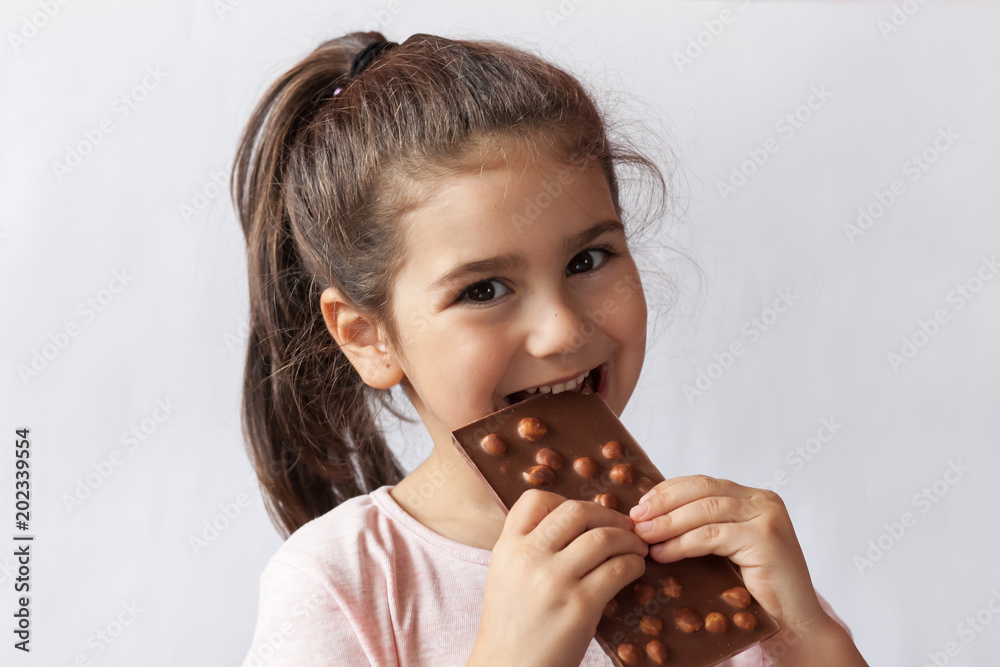 Cute child girl eating chocolate. Pretty child with chocolate. Stock