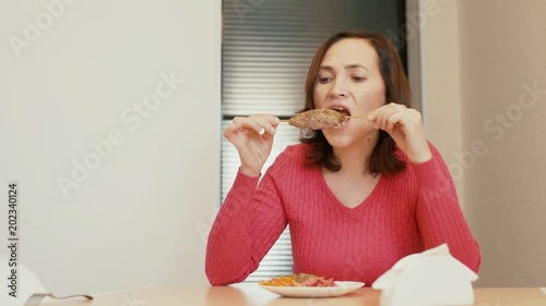 A woman is eating a shish kebab on a stick. Lulia Kebab photo
