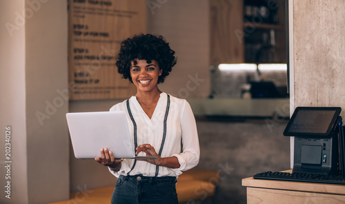Billede på lærred Female cafe owner with laptop
