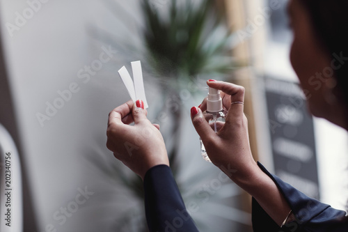 Cropped image of woman spraying perfume on litmus strips at workshop photo