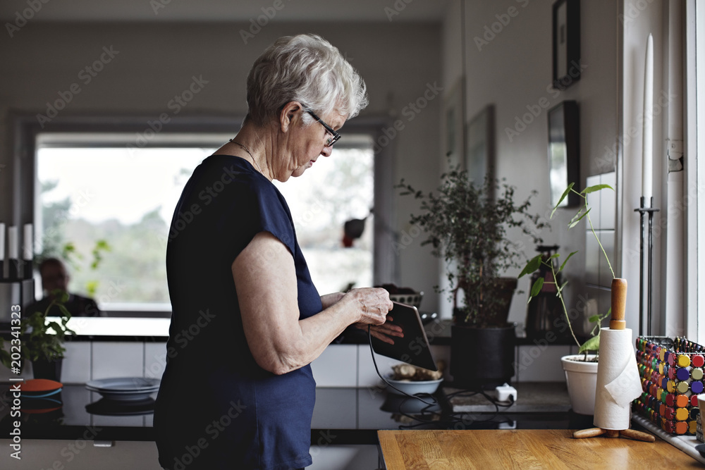 Senior woman charging tablet Senior woman charging tablet