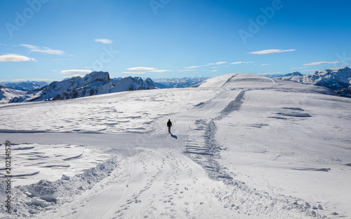 Hiker walking towards the top of the mountain while crossing a snowfield © Adrian Funk