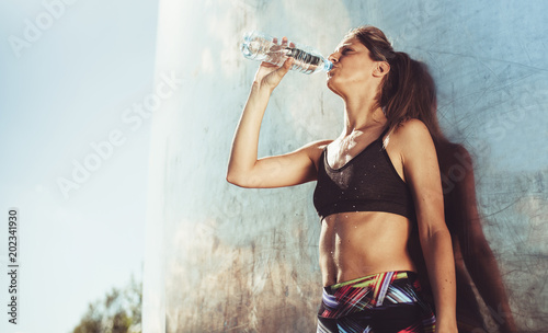 Young woman with fit body stretching against reflective background. photo