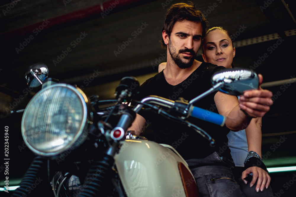 Couple looking at the mirror while sitting on a motorcycle