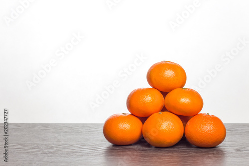 Mandarynki leżące na blacie. Piramida ułożona z mandarynek. Owoce cytrusowe na białym tle.  photo