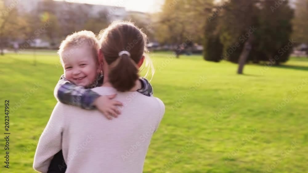 Happy mother hugs and whirls with her little son in park at sunset Happy mother hugs and whirls with her little son in park at sunset