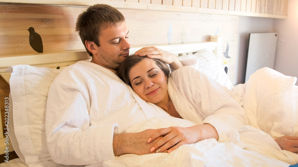 Portrait of beautiful young couple lying in bed and embracing Portrait of beautiful young couple lying in bed and embracing