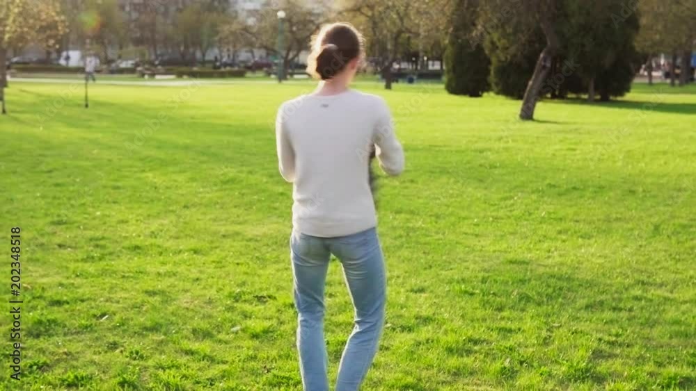 Mother holds her son by arms and whirls with him in spring park at sunset