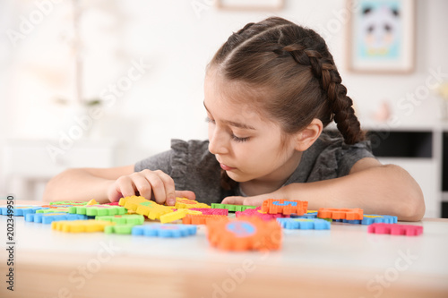 Foto Little autistic girl playing with puzzles at home
