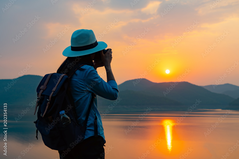 Fototapeta premium Beautiful female tourists stand on the sunset over the lake.