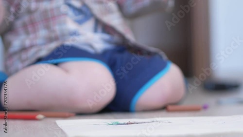Cute boy in funny glasses draws with both hands on paper at home