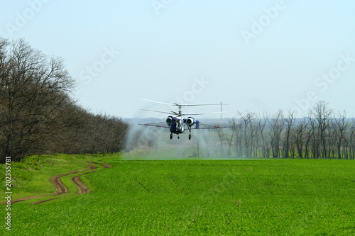 Helicopter with spray above agricultural field on the farm in spring