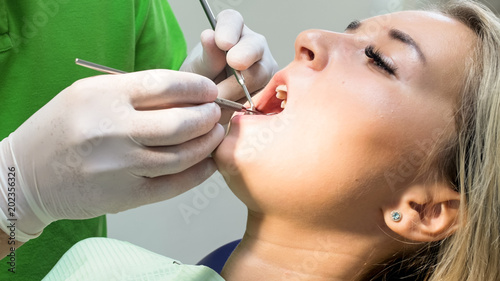 Closeup image of dentist's hand in latex protective gloves gloves treting patient's teeth with special instruments