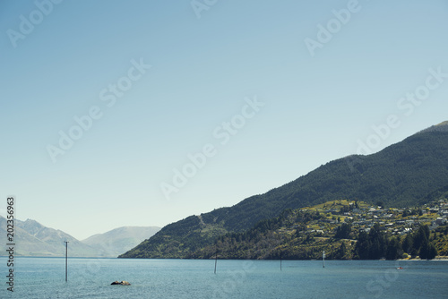 Paisaje de montaña verde bajo cielo azul despejado frente un lago en Nueva Zelanda.  © josemanuelerre