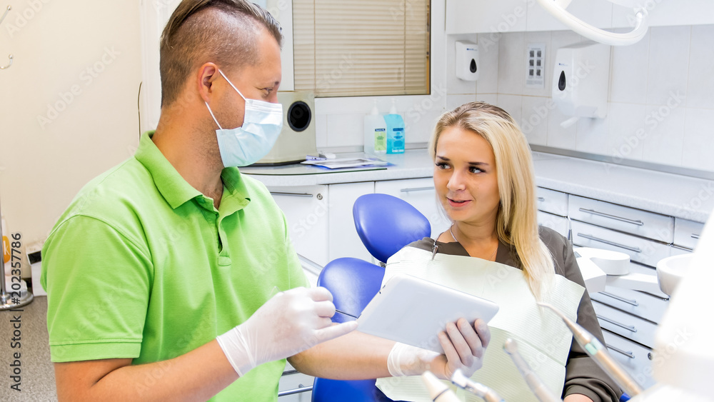 Male dentist talking to his patient and showing digital tablet Male dentist talking to his patient and showing digital tablet