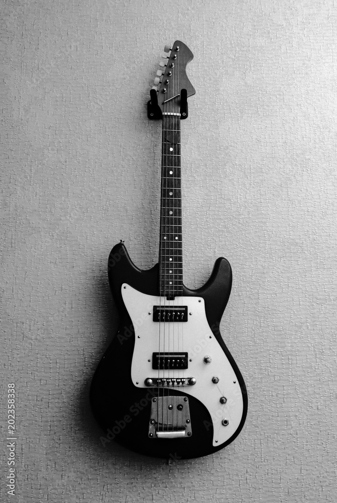 Black and white picture of old vintage electric guitar hanging on