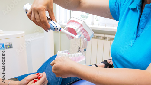 Valokuva Closeup image of dentist educating patient about cleaning teeth with electric to