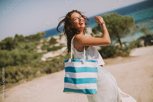 Pretty young woman with bag on the beach