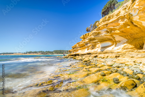 Amazing coast line called Painted Cliffs with orange yellow colored sand limestone rocks and geology structures at shore, perfect expedition on warm sunny clear day, Maria Island, Tasmania, Australia