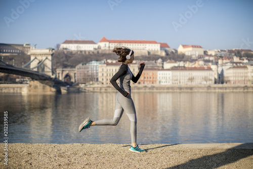 Canvas Print Young female athlete running on the waterfront in Budapest, Hungary