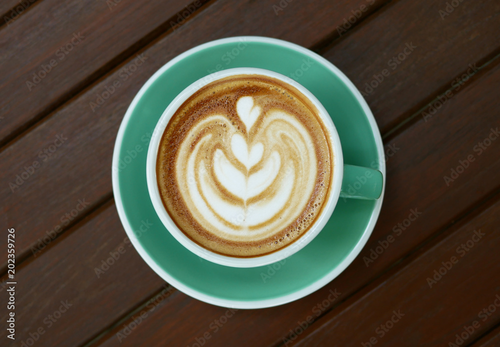 Top view of hot coffee cappuccino latte art in jade color cup on wooden background Top view of hot coffee cappuccino latte art in jade color cup on wooden background