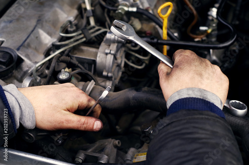 Hands of a mechanic in oil and fuel oil with a wrench during repair of the engine