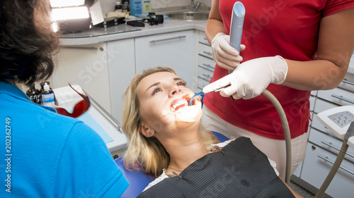 Closeup image of dentist assistant using saliva ejector photo