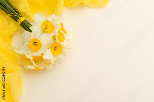 Fototapeta Naklejka Na Ścianę i Meble -  White daffodil bouquet with yellow textile decoration on pastel background with copy space.
