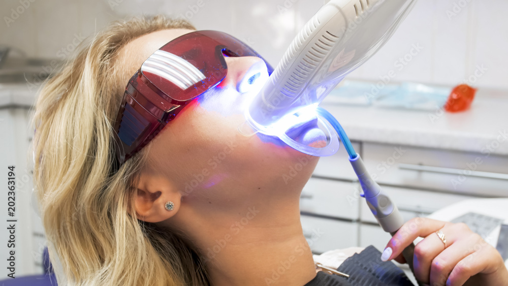 Φωτογραφία Closeup image of young woman in protective glasses sitting in dentist chair duri