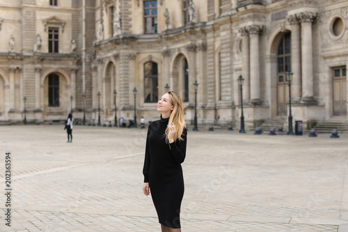 Female person in black dress standing near Louvre. Concept of visiting France and historic buildings.