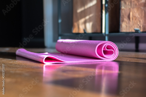 Yoga mat on the wooden floor. One pink yoga man on a brown wooden floor. 