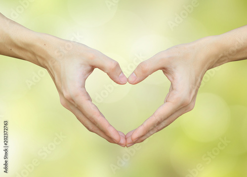 close up man hands making heart on blurred bokeh nature backgrounds for lover fall in love concept.