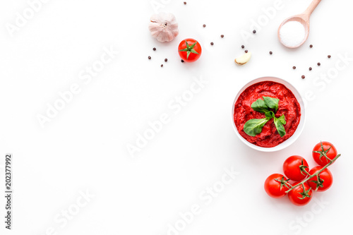 Ingredients for tomato sauce. Cherry tomatoes, garlic, green basil, black pepper, salt in spoon on white background top view copy space