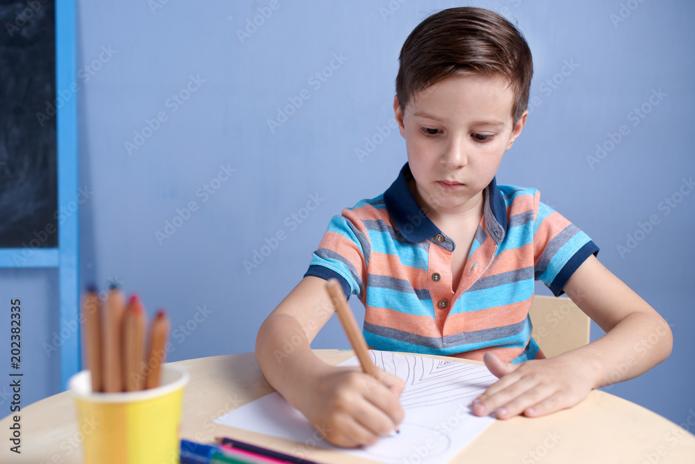 European boy spending time drawing with colorful pencils at home. European boy spending time drawing with colorful pencils at home.