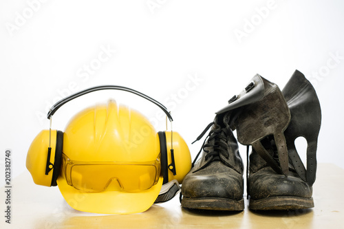 Protective helmet and work boots on a wooden table. Safety and health protection accessories for construction workers.
