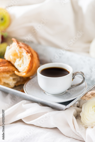 Fresh Croissant, Cup of Coffee and Ranunculus Flowers. Breakfast