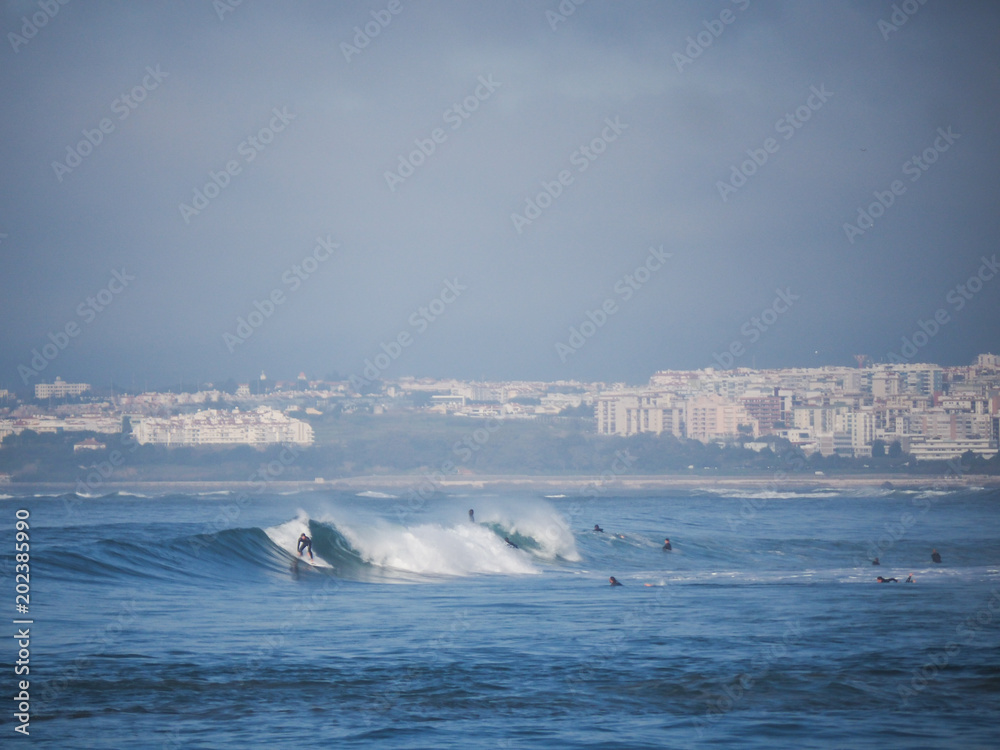 Surfer surfing waves at costa da caparica, nearby the city of lisbon Surfer surfing waves at costa da caparica, nearby the city of lisbon