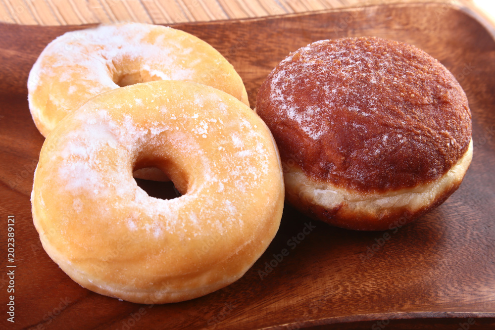 Assorted Homemade Doughnuts with Jelly filled and powdered sugar on wooden salver. Selective focus.