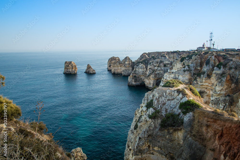 Fototapeta Krajobrazowy widok linia brzegowa Lagos sunie w tle Farol da Ponta da Piedade, Algarve, Portugalia