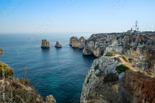 Fototapeta Krajobrazowy widok linia brzegowa Lagos sunie w tle Farol da Ponta da Piedade, Algarve, Portugalia