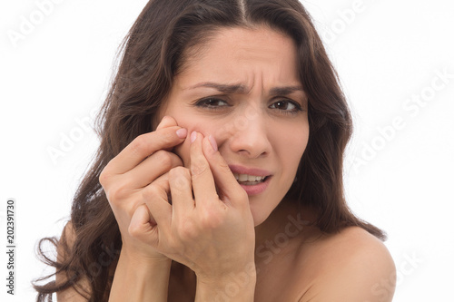 Close up of annoyed brunette squishing pimples. Posing on camera. Mid age woman over 35 years old beauty concept.